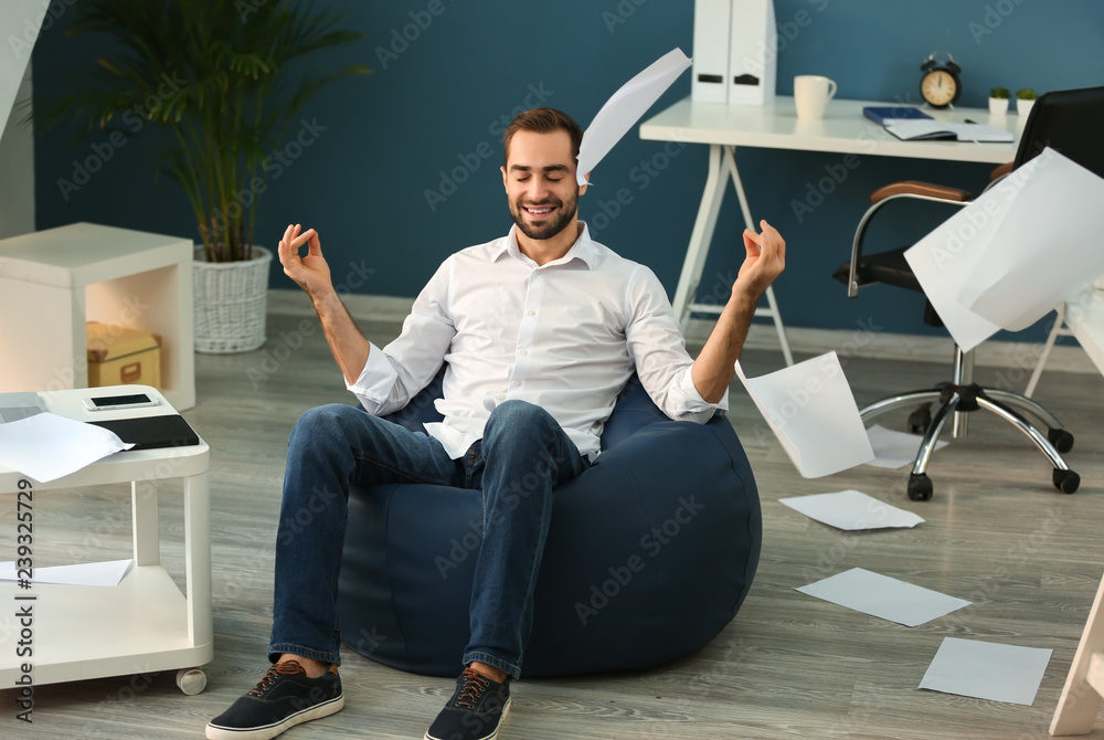 Businessman meditating with a lot of work in office