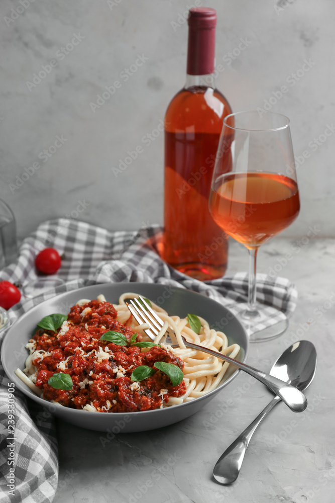 Plate with delicious pasta bolognese and wine on grey table