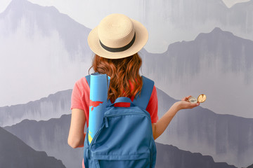 Female tourist with backpack near grey wall