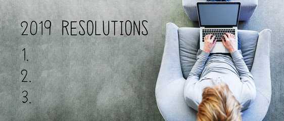 Wall Mural - 2019 Resolutions with man using a laptop in a modern gray chair