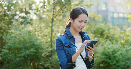 Canvas Print - Woman sending sms on cellphone under sunset