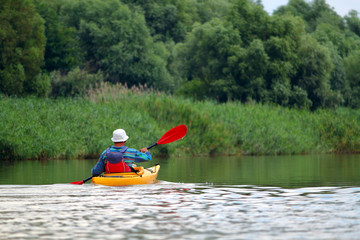 Rear view of kayaker man paddle yellow kayak on Danube river. Summer kayaking. Concept for adventure, travel, action, lifestyle