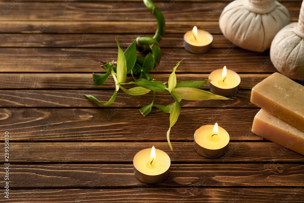 Beautiful spa composition with burning candles and soap bars on wooden table