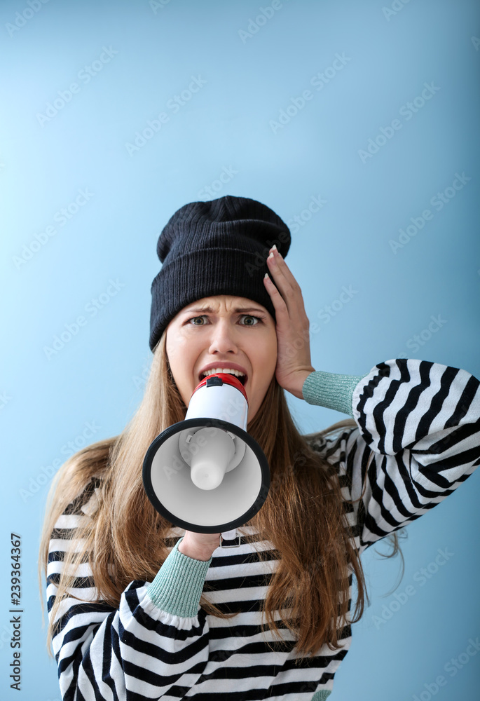 Shocked young woman with megaphone on color background