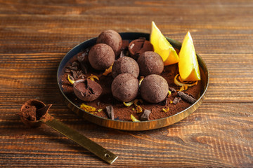 Plate with sweet truffles on wooden table