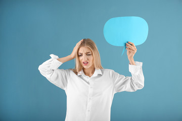 Worried young woman with blank speech bubble on color background