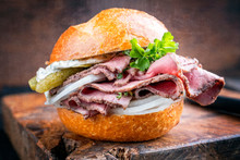 Traditional Sliced Cold Cuts Roast Beef Sandwich With Onion, Gherkin And Remoulade Offered As Closeup On An Old Wooden Board