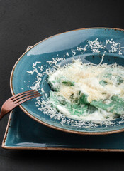 Wall Mural - Ravioli with spinach and basil, parmesan cheese on plate over black stone background. Clean eating, vegetarian food concept