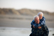 © Erickson Stock - Smiling mature man piggybacking his wife along a remote beach.