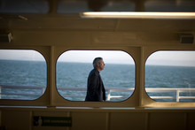Businessman Walking Past A Window On A Boat Out At Sea.