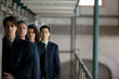 © Erickson Stock - Mid-adult business woman standing with three colleagues in an empty derelict prison.