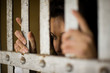 © Erickson Stock - Mid-adult business woman behind bars in a derelict building.