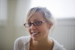 © Erickson Stock - Portrait of young adult woman wearing glasses in a room.