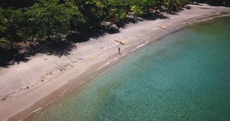 Wall Mural - Aerial drone view of girl walking on the shoreline in a tropical paradise beach in a Caribbean island