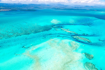 aerial view of idyllic azure turquoise blue lagoon of west coast barrier reef, with mountains far in