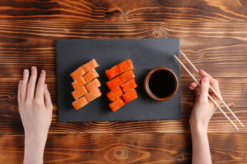 japanese roll flat lay with hand. set of california nad philodelphia rolls on slate plate and wooden background