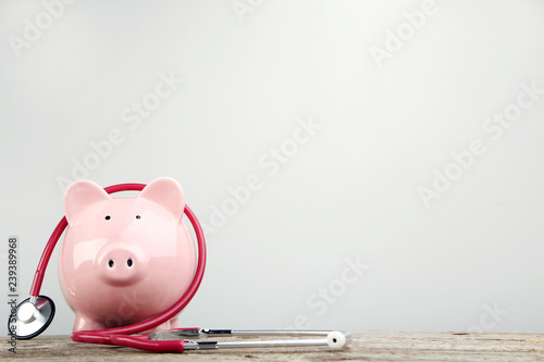 Fotomural Pink piggy bank with stethoscope on wooden table