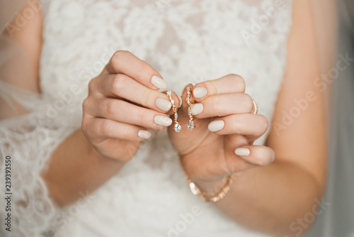 Cuadros en Lienzo Women's wedding jewelry (earrings) in the hands of the bride, selective focus