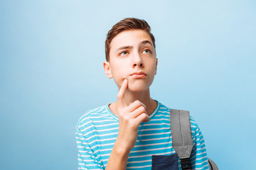 Pensive teenager guy, on a blue background