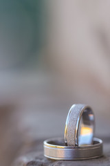 White gold wedding rings stand on the black rock. Blurred background