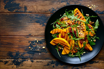 Wall Mural - Grilled pumpking warm salad with arugula, walnuts and pomegranate seeds.Top view with copy space.