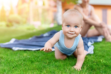 Portrait Of Cute Little Caucasian Boy Having Fun In Garden With Mother. Child Crawling On Green Grass Lawn During Walk With Mom In Yard. Happy Childhood And Baby Healthcare