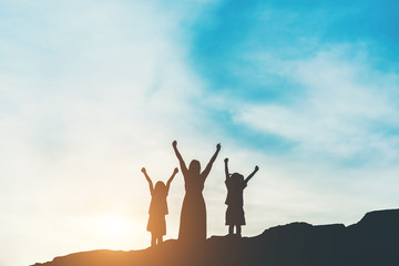 Wall Mural - Silhouette of mother with her daughter standing and sunset