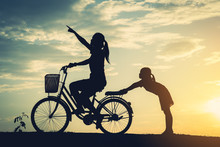 Silhouette Of Mother With Her Daughter And Bicycle