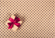 © alatielin - Gift with red bow. Gift box on polka dot paper background. Copy space