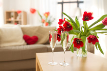 Valentines Day, Romantic Date And Holidays Concept - Two Champagne Glasses And Red Tulip Flowers On Table In Living Room Or Home