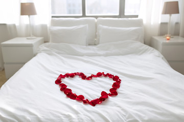 Wall Mural - valentines day, romantic date and holidays concept - bed decorated with heart made of red petals in bedroom at home