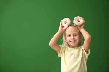 Canvas Print - Cute little girl with donuts on color background