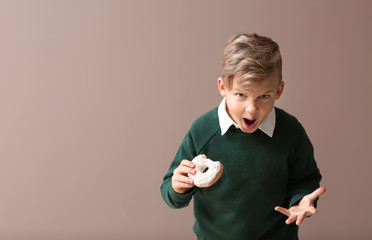 Wall Mural - Angry little boy with donut on color background