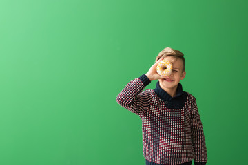 Wall Mural - Cute little boy with donut on color background