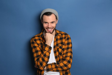 Fashionable young man in checkered shirt on color background