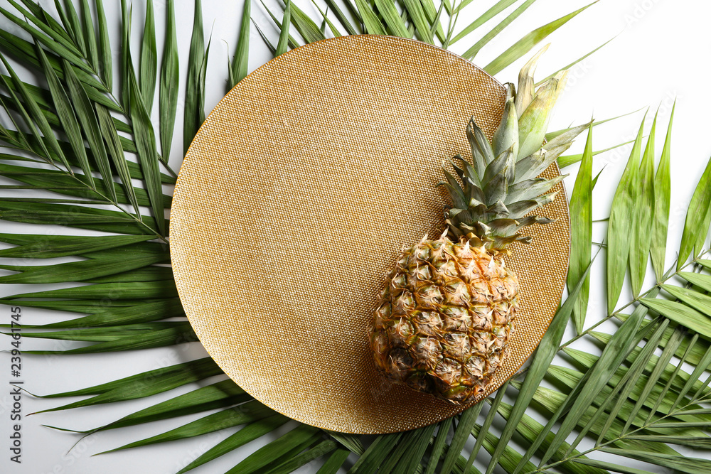 Plate with ripe tasty pineapple and palm leaves on white background