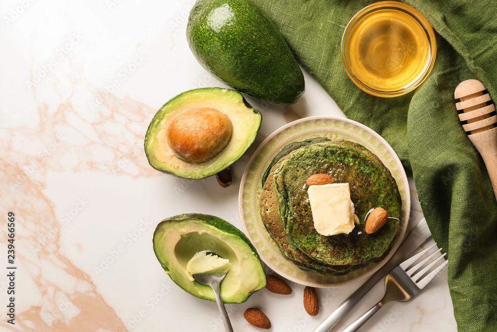 Tasty green pancakes with avocado on light table