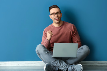 Sticker - Successful young man with laptop sitting near color wall