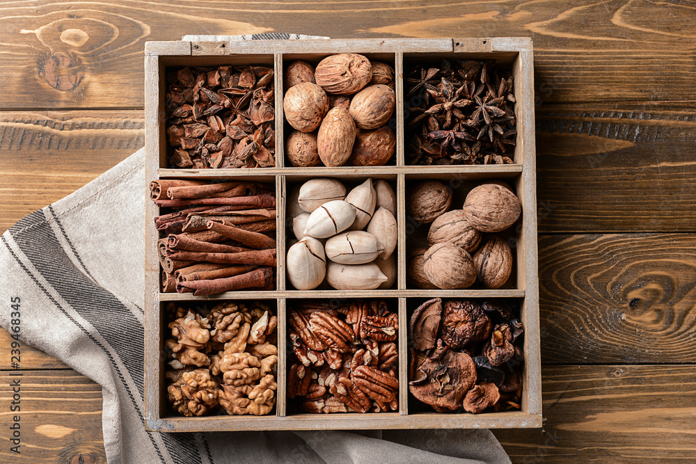 Assortment of nuts and spices in divided box on wooden table