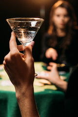 cropped image of woman holding glass of cocktail at table in casino