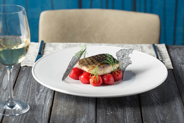 Tasty baked fish with cherry tomatoes, spices on dark rustic background. Grilled delicious fish. Diet and healthy food.