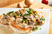Two Pork Chops With Sauce Made From Cream And Mushrooms