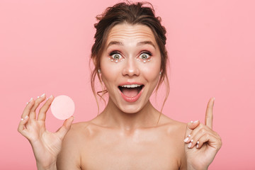 Canvas Print - Shocked happy young woman posing isolated over pink wall background holding cotton disk.