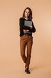 © Drobot Dean - Photo of smiling woman 20s standing and holding laptop, isolated over beige background