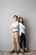 © Drobot Dean - Full length of cheerful asian couple standing back to back