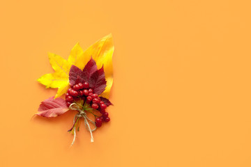 Wall Mural - Top view, flat lay autumn fall mockup with decorative composition from dried orange red leaves and viburnum berries. Postcard, card on orange background with copy space.