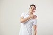 Indifferent  guy dressed in a white t-shirt and jeans is on a white background in the studio