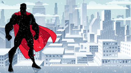 Wall Mural - Silhouette of superhero standing tall on winter city background with copy space.