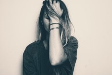 Blonde Girl Covering Her Face With Her Left Hand. Image In Black And White Noir. Depicting Sad, Worried, Frustrated Emotion, Like The Female Messed Up Or Is Stressed About Something, Unhappy, Unsure
