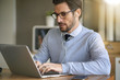 © goodluz - Businessman working on laptop with headphones in office